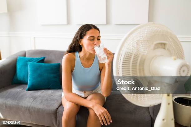Woman Enjoying A Cold Drink In Front Of The Fan Stock Photo - Download Image Now - Heat Wave, Heat - Temperature, Water
