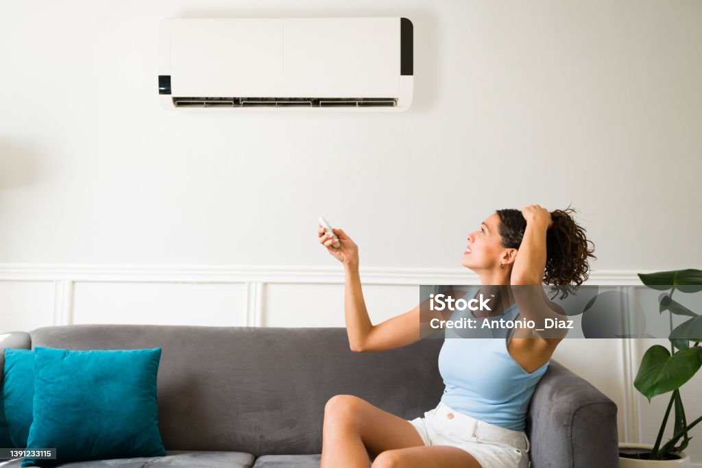 Suffering because of a broken air conditioner Hot young woman feeling sweaty during a heat wave because her air conditioning is not working Air Conditioner Stock Photo