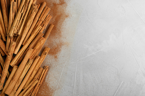 Aromatic cinnamon sticks and powder on grey table, flat lay. Space for text