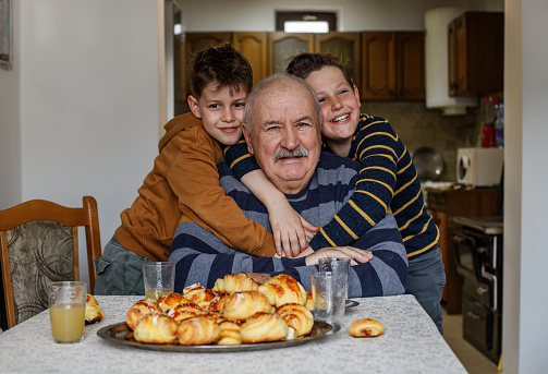 Cheerful aged man smiling and embracing cute boys