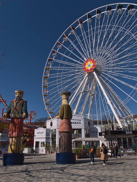 les touristes profitent de leur temps dans le parc d’attractions populaire wurstelprater près de wiener prater à vienne, en autriche, avec la grande roue blumenrad par une journée ensoleillée au printemps. - wiener wurstelprater photos et images de collection