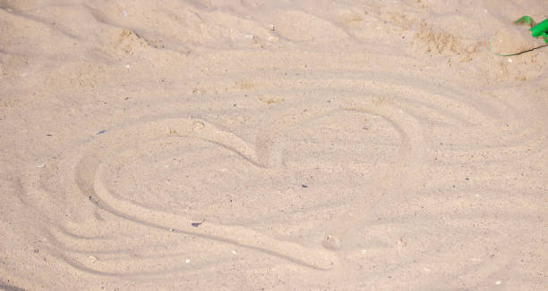 istock Heart drawn in the sand. Beach background. Top view 1391239476