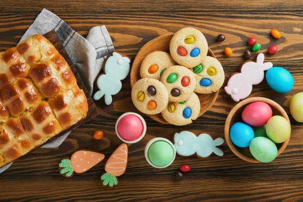 istock Easter hot cross buns with colored eggs Easter gingerbread rabbits and cookies over dark brown plank wooden old table background. Spring holiday baking concept. Easter table setting. Top view. Mock up 1391242201