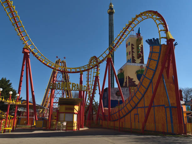 blick auf die geschlossene achterbahn boomerang im freizeitpark wurstelprater beim wiener prater in wien, österreich an sonnigen frühlingstagen mit fallturm im hintergrund. - wiener wurstelprater stock-fotos und bilder