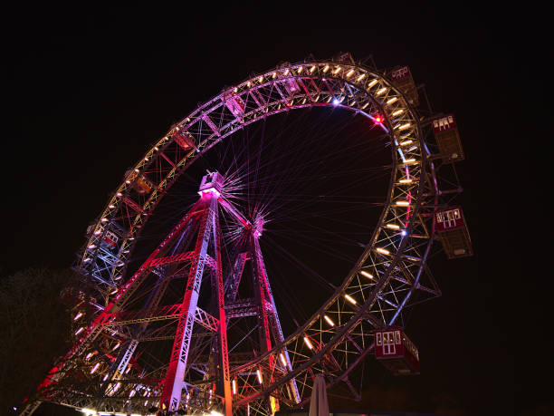 superbe vue à angle bas de la grande roue populaire avec jante illuminée colorée la nuit dans le parc d’attractions prater (wurstelprater) à vienne, en autriche. vu. - vienna ferris wheel night prater park photos et images de collection