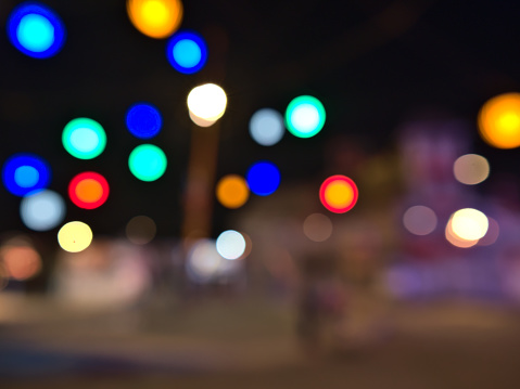 Defocused (blurred) view at night of a square illuminated by colorful lights at amusement park Wurstelprater near Wiener Prater in city Vienna, Austria. Image out of focus.
