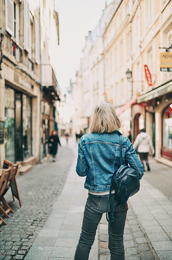 Rear view of a woman strolling down Rue Froide in the Normandy city of Caen, France on a spring day.