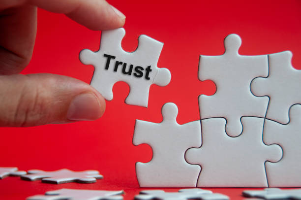 istock Trust text on jigsaw puzzle with red background - Working relationship and trust concept 1391245376