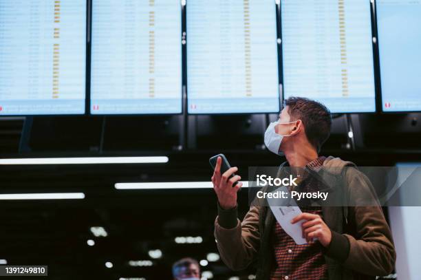 Checking The Flight Schedule Stock Photo - Download Image Now - Nomadic People, Passenger, Protective Face Mask