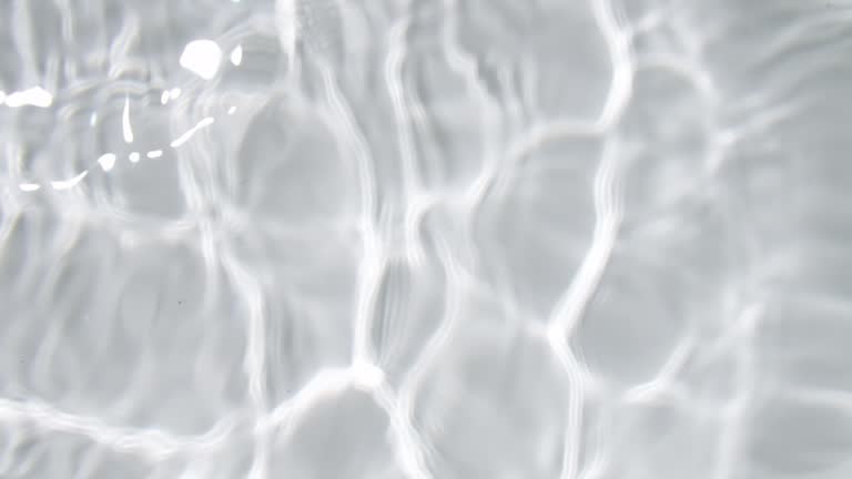 the surface of clear water with ripple waves from left direction in a white bathtub to water calm