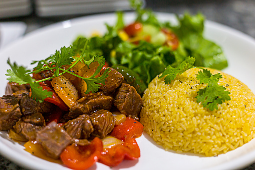 Asian fried rice served with beef, bell peppers, vegetables. Beautifully presented on a white porcelain plate