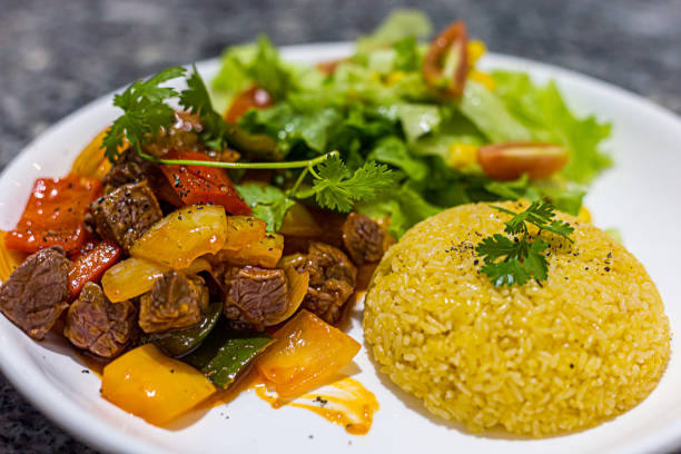 Asian fried rice served with beef, bell peppers, vegetables. Beautifully presented on a white porcelain plate