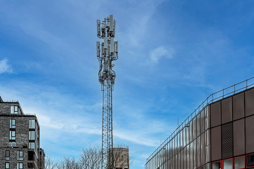 5G cell tower in the city against a blue sky: communication tower for mobile phones and video data transmission