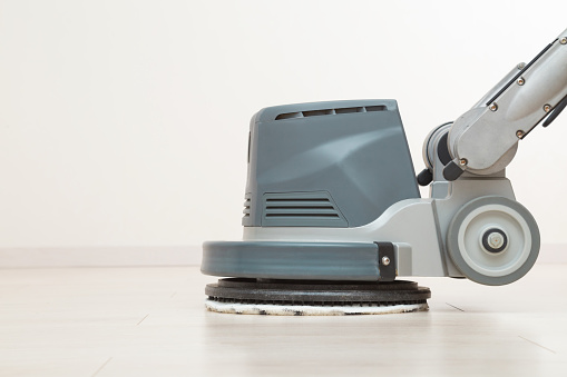 A robotic vacuum cleaner cleans the floor and carpets while a mother lies on the couch with her book and relaxes