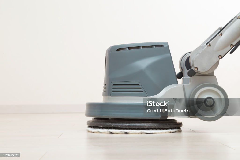 Professional disc machine with microfiber soft pad polishing and waxing light laminate floor surface at home room. Closeup. Commercial service. Side view. Flooring Stock Photo
