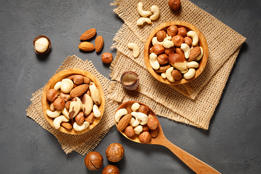 Various nuts in bowl - cashew, hazelnuts, almonds, brazilian nuts and macadamia on a gray stone background. Top view.