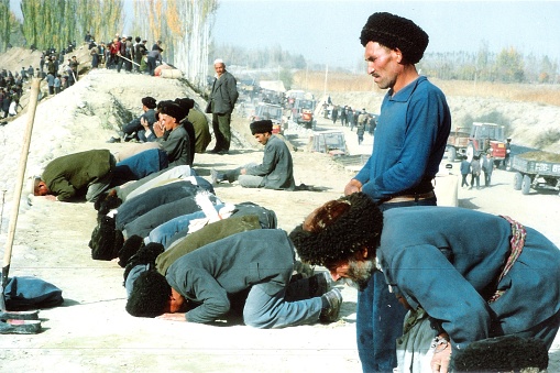 People pray at winter canal sites in Cele County, in southern Xinjiang province.Film photo in 1996