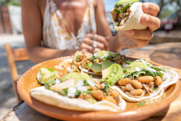 mujer joven comiendo tacos veganos comida callejera - guacamole avocado mexican culture food fotografías e imágenes de stock