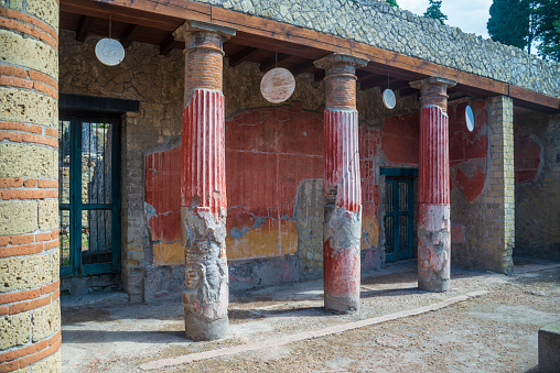 Building columns holding up a roof over a portico that still carry the original color they were painted prior to the eruption of Mount Vesuvius in 79 AD that buried the town in lava.