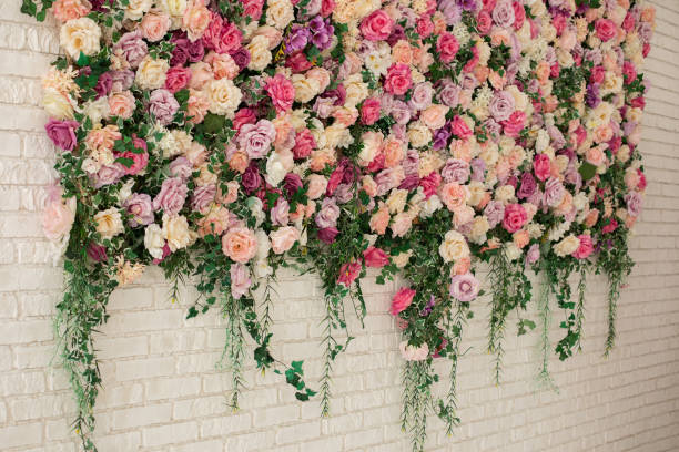 istock Interior wedding party decor. Spring flowers on wall building. Beautiful decorative colorful roses and peonies on brick white wall.  Wall with curly Flowers. Brick wall with beautiful flowers in room 1391264807