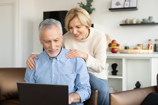 Mature couple call to family doctor, make video conference or watching video online on laptop together. Concept of modern technology and telemedicine