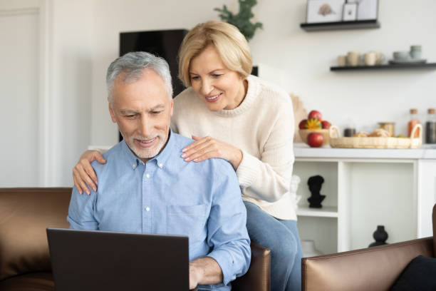 Mature family couple watching video on laptop Mature couple call to family doctor, make video conference or watching video online on laptop together. Concept of modern technology and telemedicine medicare stock pictures, royalty-free photos & images