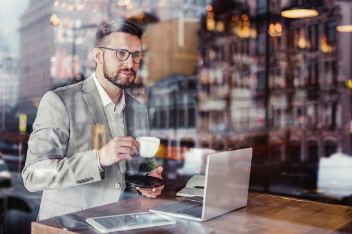 Portrait of a handsome young businessman siting in the coffee shop and drinking coffee