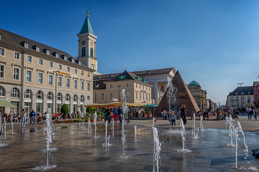 View of the old facades of white and pink buildings with high windows, arches, statues and decorative elements. Central square with the statue of Neptune. Blue sky. Poland, Gdansk, April 2023