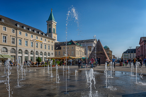 Karlsruhe, Germany - March, 26. 2022: View to town square with fountain and pyramid in Karlsruhe. Located in pedestrian zone.