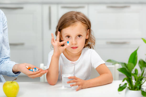 子供はカプセルを見せ、薬やビタミンサプリメントを食べ物に持っていく - nutritional supplement pill eating food ストックフォトと画像