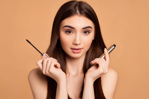 istock woman hold mascara isolated on beige background 1391272953