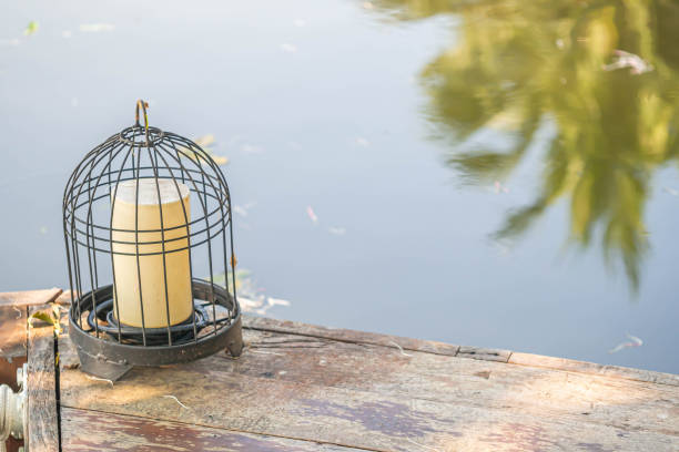 Home outdoor decoration with lamp inside birdcage on ancient wooden floor near the river stock photo