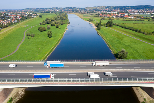 Highway bridge with car and truck traffic over the canal in summer landscape, aerial view.