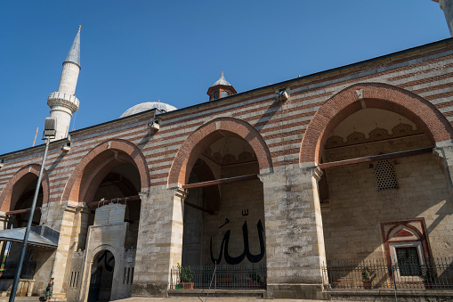 Edirne Turkey - August 27, 2021 : Eski (old) Mosque in Edirne Turkey. Muslim prayers in the mosque. Calligraphy of the name of Allah on the wall.