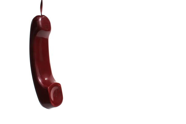 A handset from a wired telephone hangs on a white background.