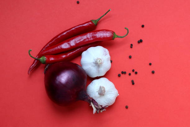 Red pepper, garlic and red onion lie on a red background