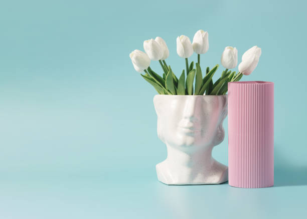 istock Antique marble head sculpture with spring flowers on a pastel blue background. 1391278564