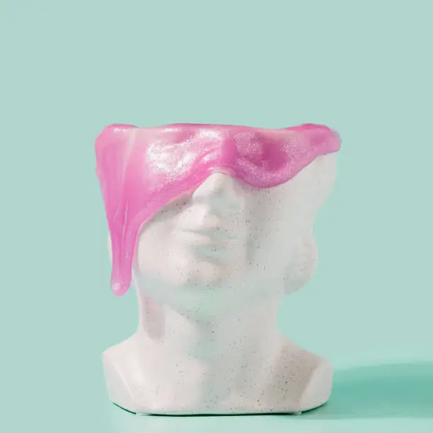 Photo of Marble sculpture head with purple slime dripping against pastel mint background.