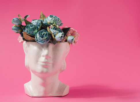 Marble statue head with spring flowers inside. Summertime colorful background.