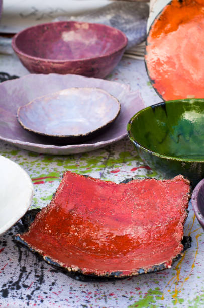 istock Handmade clay plates standing on a tablecloth in drops of paint 1391281908