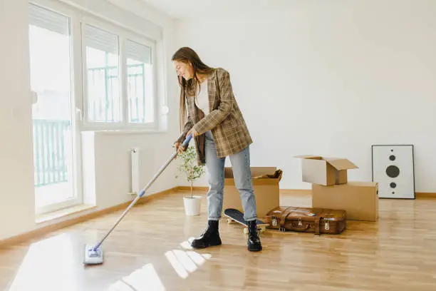 Photo of Young woman cleaning and preparing her house for moving in