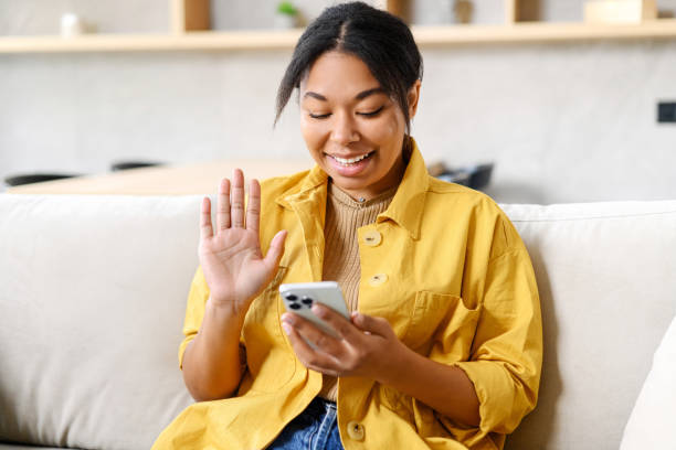 istock Happy African-American female using mobile app on smartphone for making video call 1391287394