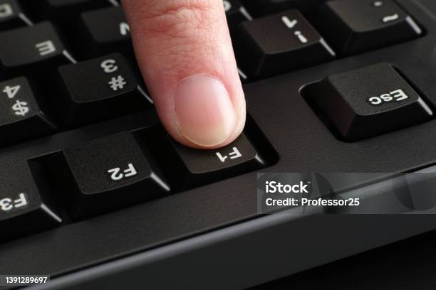 A Finger Pushing The F1 Key On A Black Computer Keyboard Stock Photo - Download Image Now