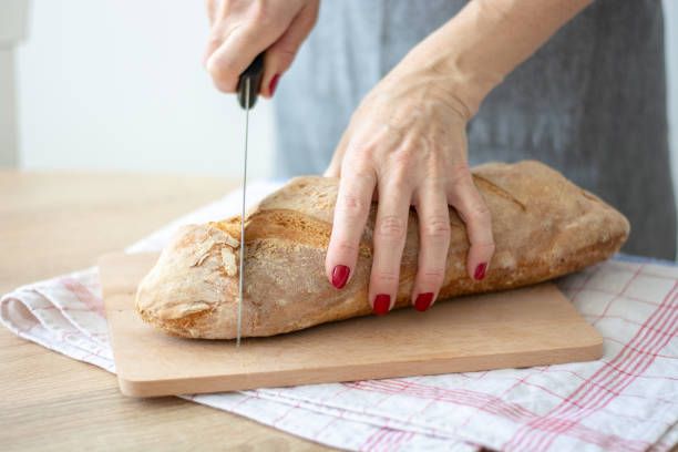 istock Woman cutting sourdough bread with knife on board 1391290921