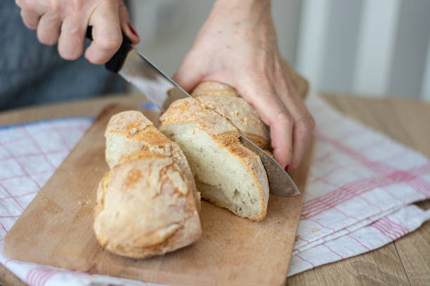 istock Woman cutting sourdough bread with knife on board 1391291109