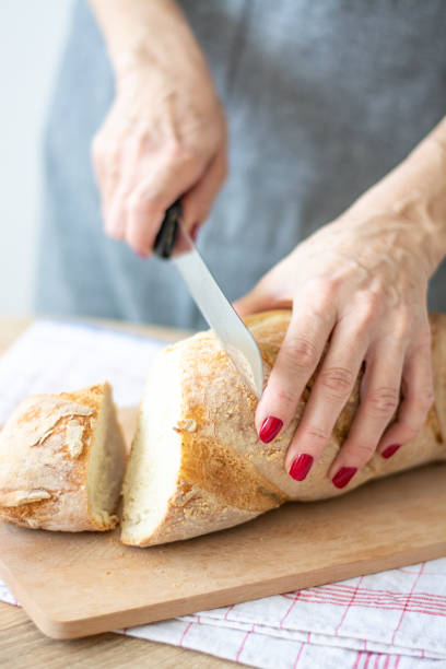 istock Woman cutting sourdough bread with knife on board 1391291140