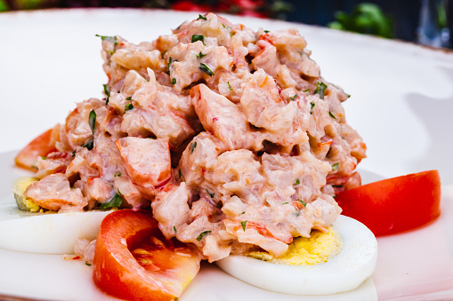 Lobster salad with egg and tomato on white plate.