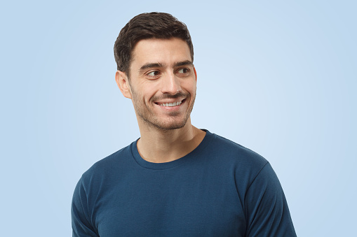 Close up portrait of smiling handsome male in blue t-shirt looking right