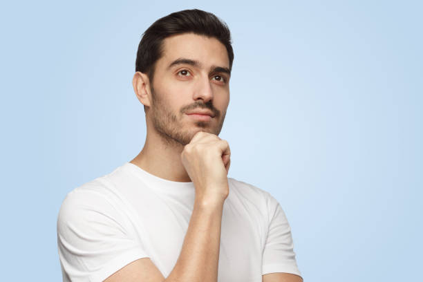 istock Attractive young man with dreamy cheerful expression thinking isolated on blue background 1391298398