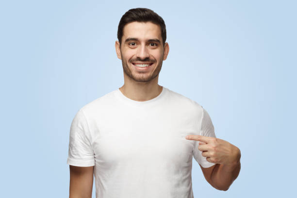 istock Young attractive casual man points with index finger at blank white t-shirt 1391298401